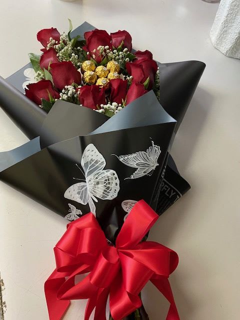 Bouquet of red roses wrapped in black paper with a red ribbon