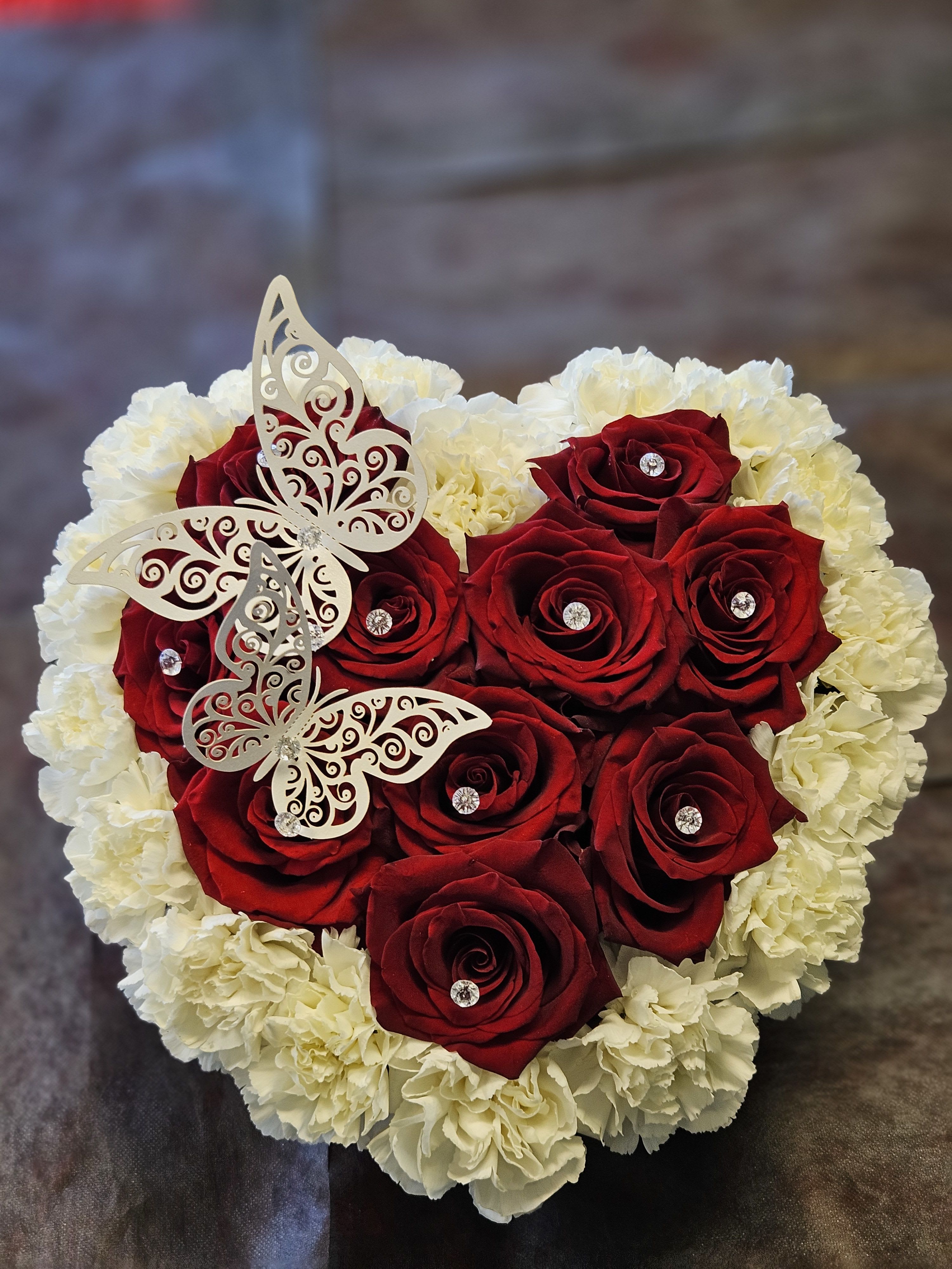 Heart-shaped bouquet of red roses and white carnations with butterfly decorations