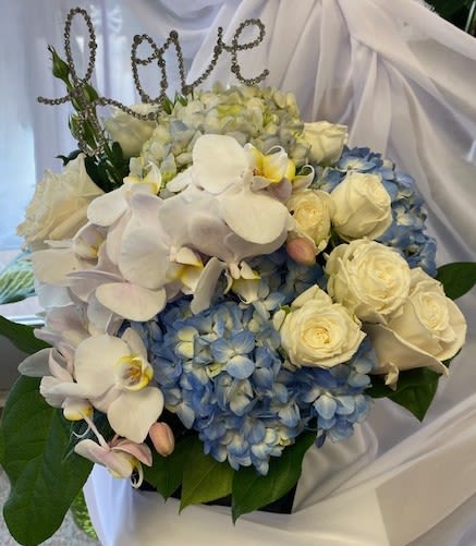 Blue hydrangeas and white roses with white orchids in a bouquet