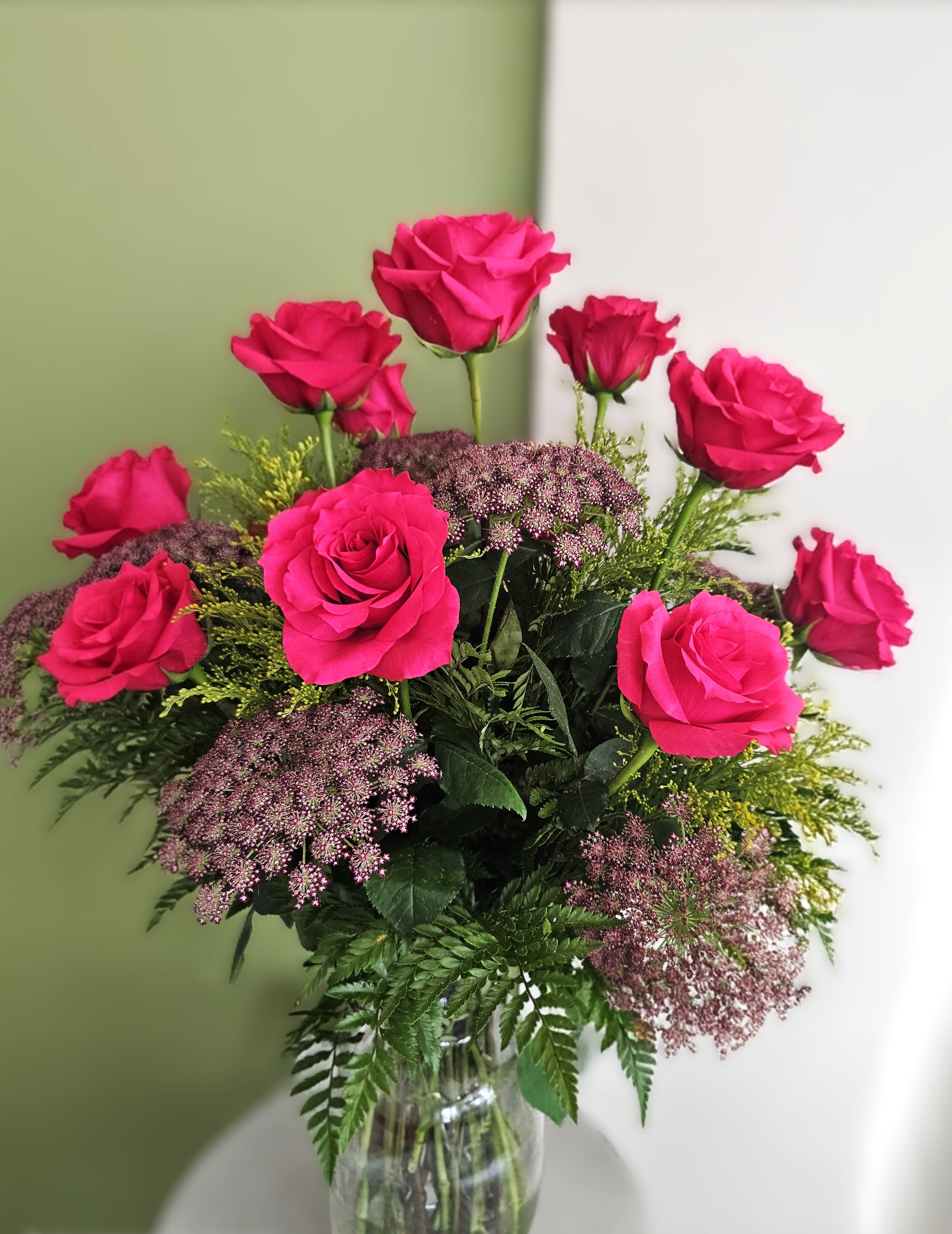 Pink roses arranged in a clear glass vase with purple filler flowers