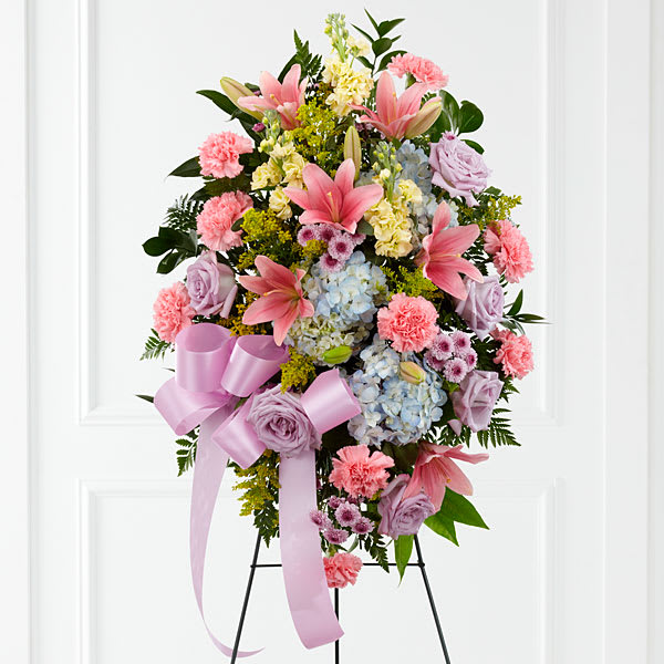 Standing floral spray with pink lilies, roses, carnations, and hydrangeas on an easel