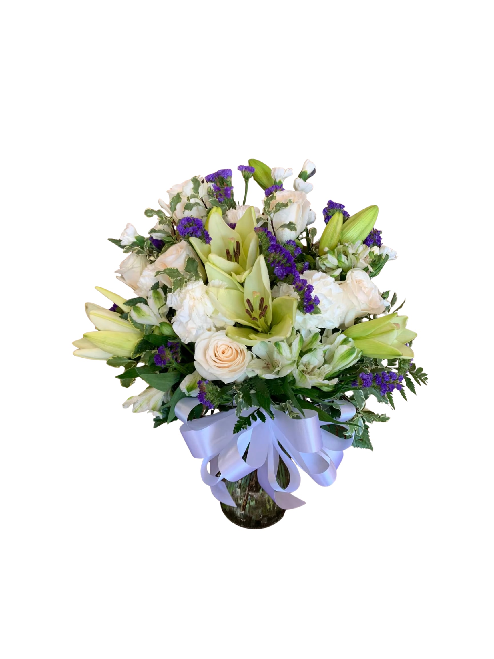 Bouquet of white lilies, roses, and purple filler flowers in a glass vase