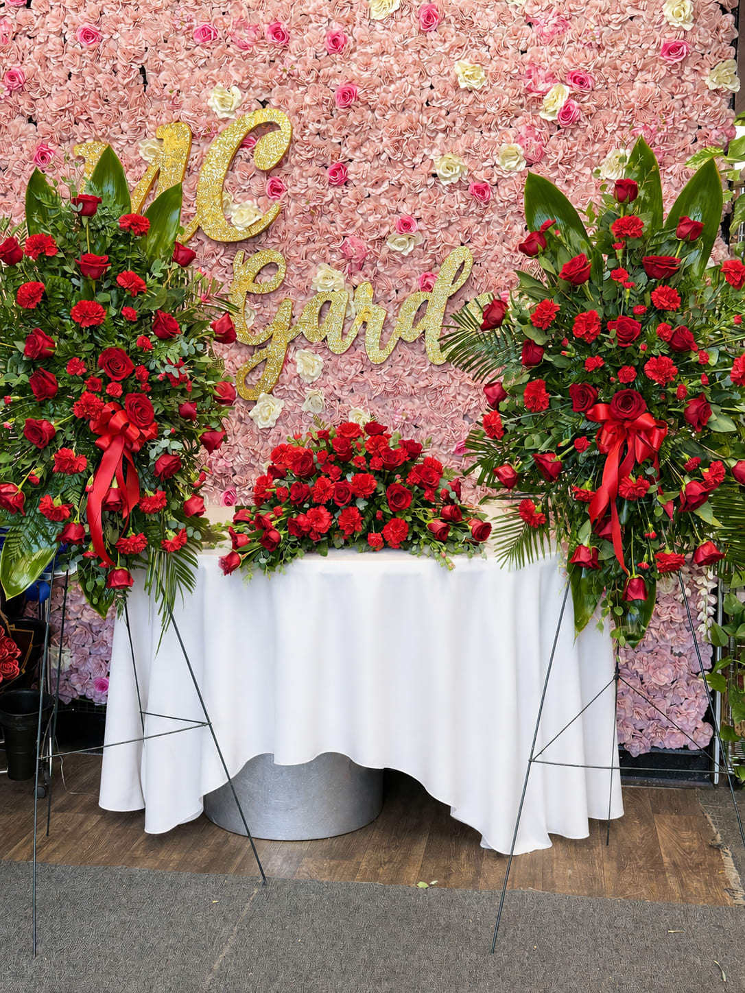Large floral display with red roses and carnations against a pink flower wall