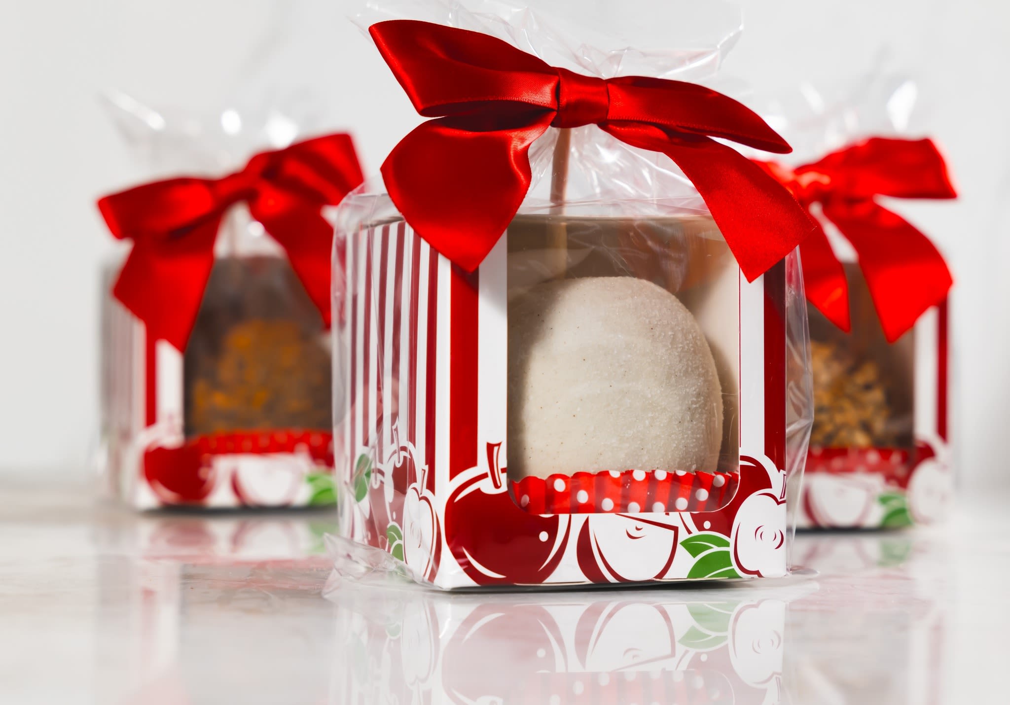 Three wrapped gift boxes with red bows and round treats inside