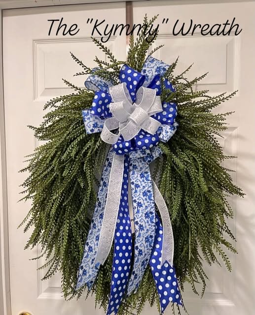 Green wreath with blue and white ribbon bow on a door