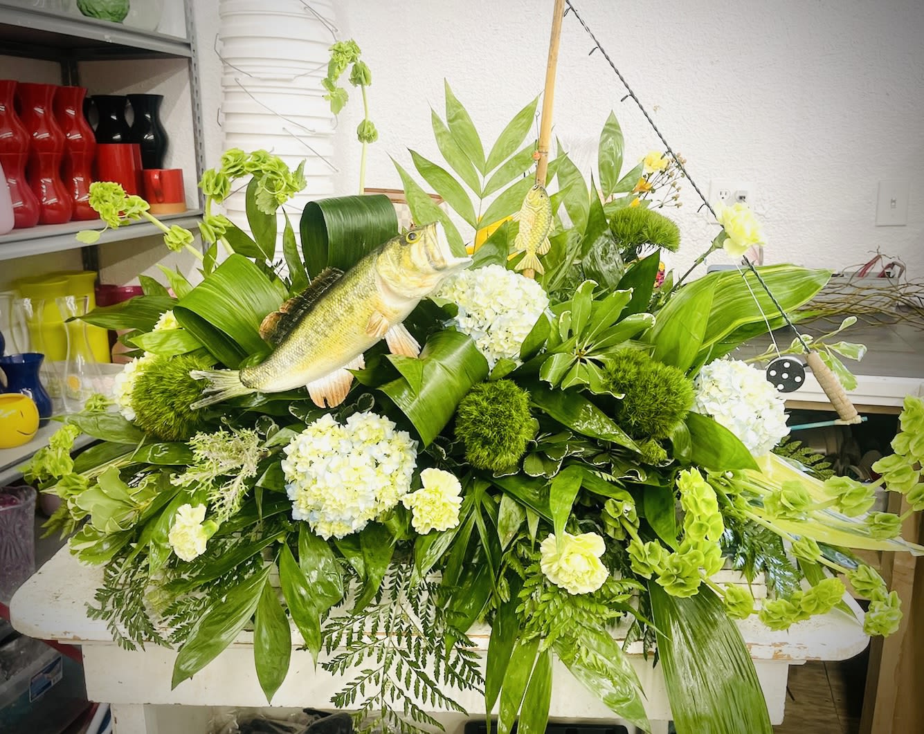 Large green floral arrangement with white blooms and a fish centerpiece