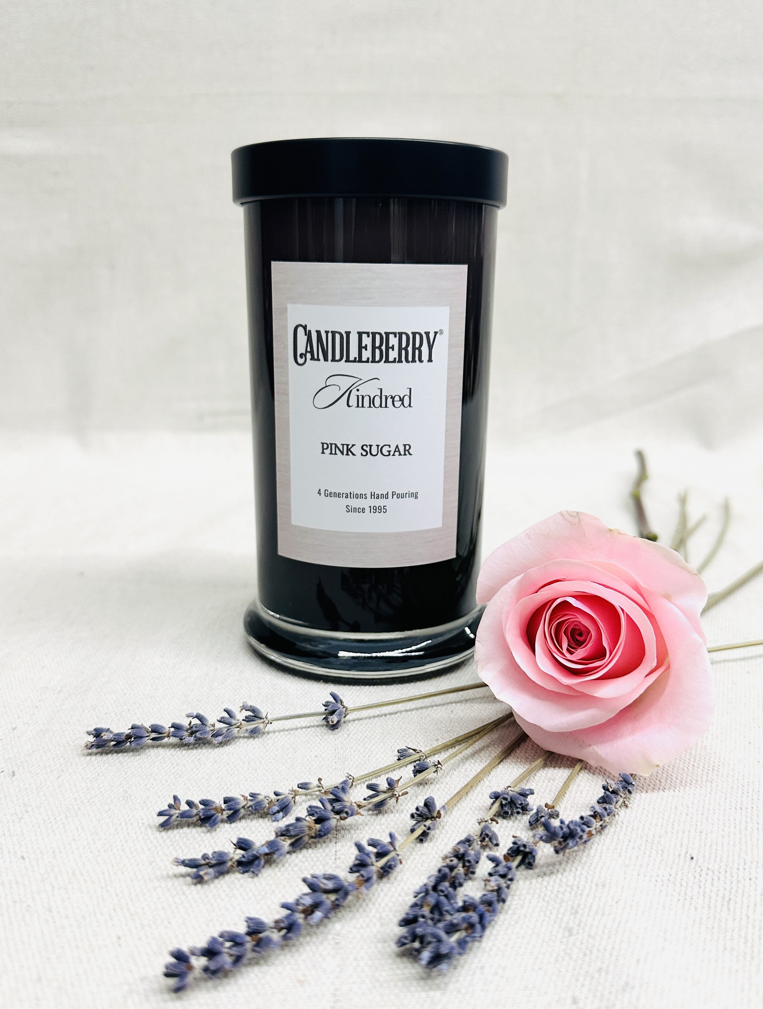 Black candle jar with a pink rose and lavender sprigs