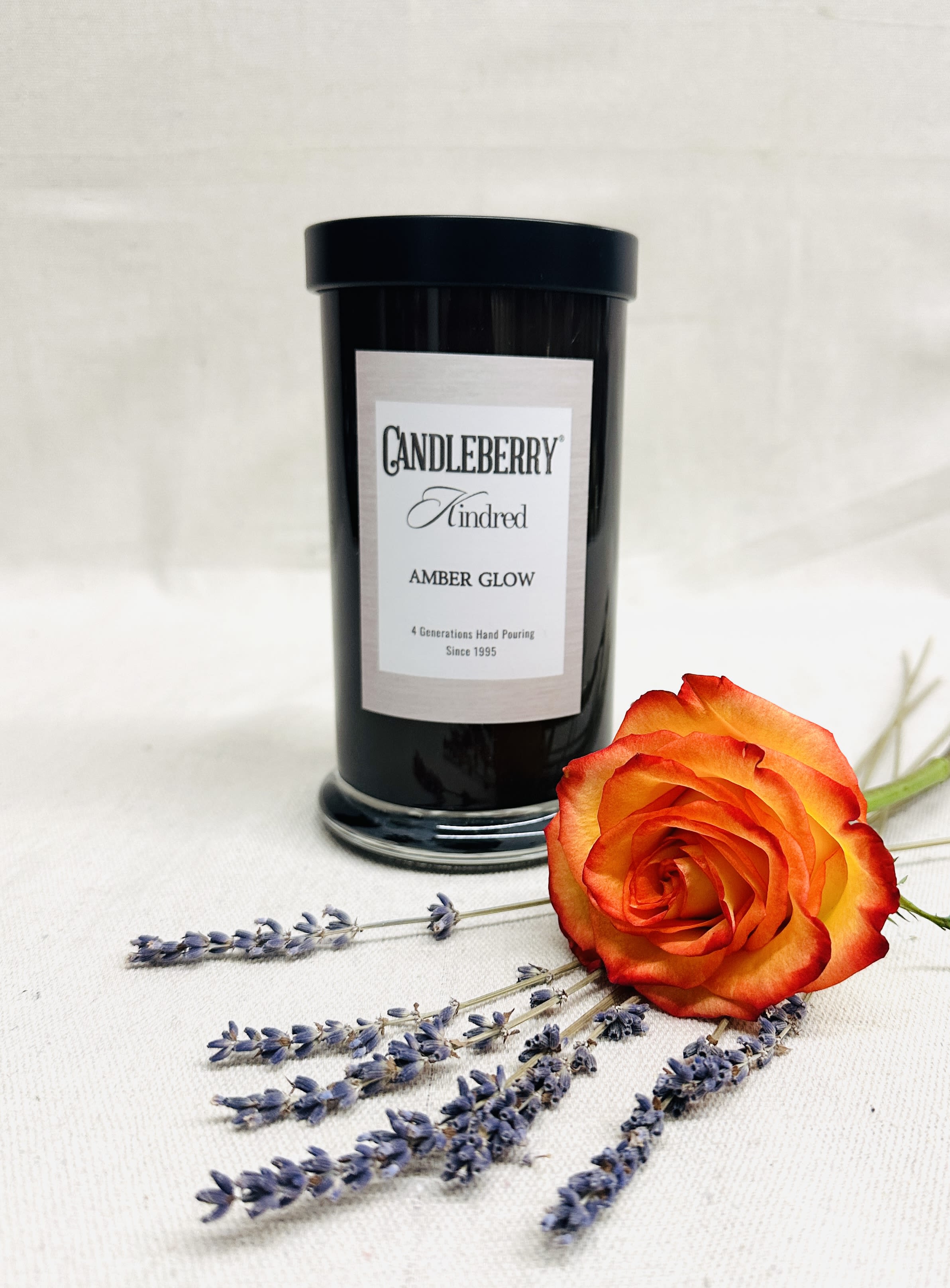 Black candle jar with an orange rose and lavender sprigs
