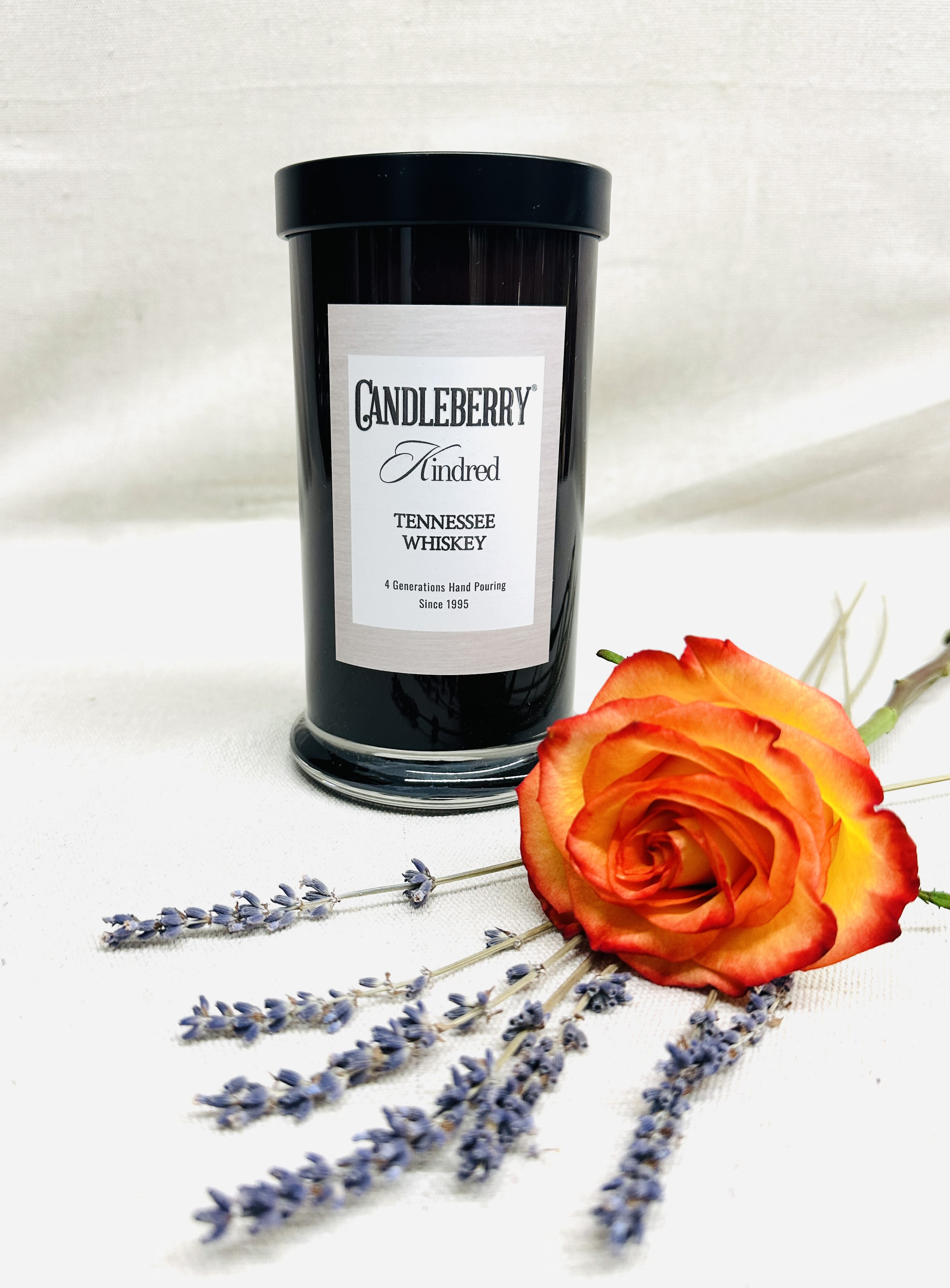 Black candle jar with an orange rose and lavender sprigs