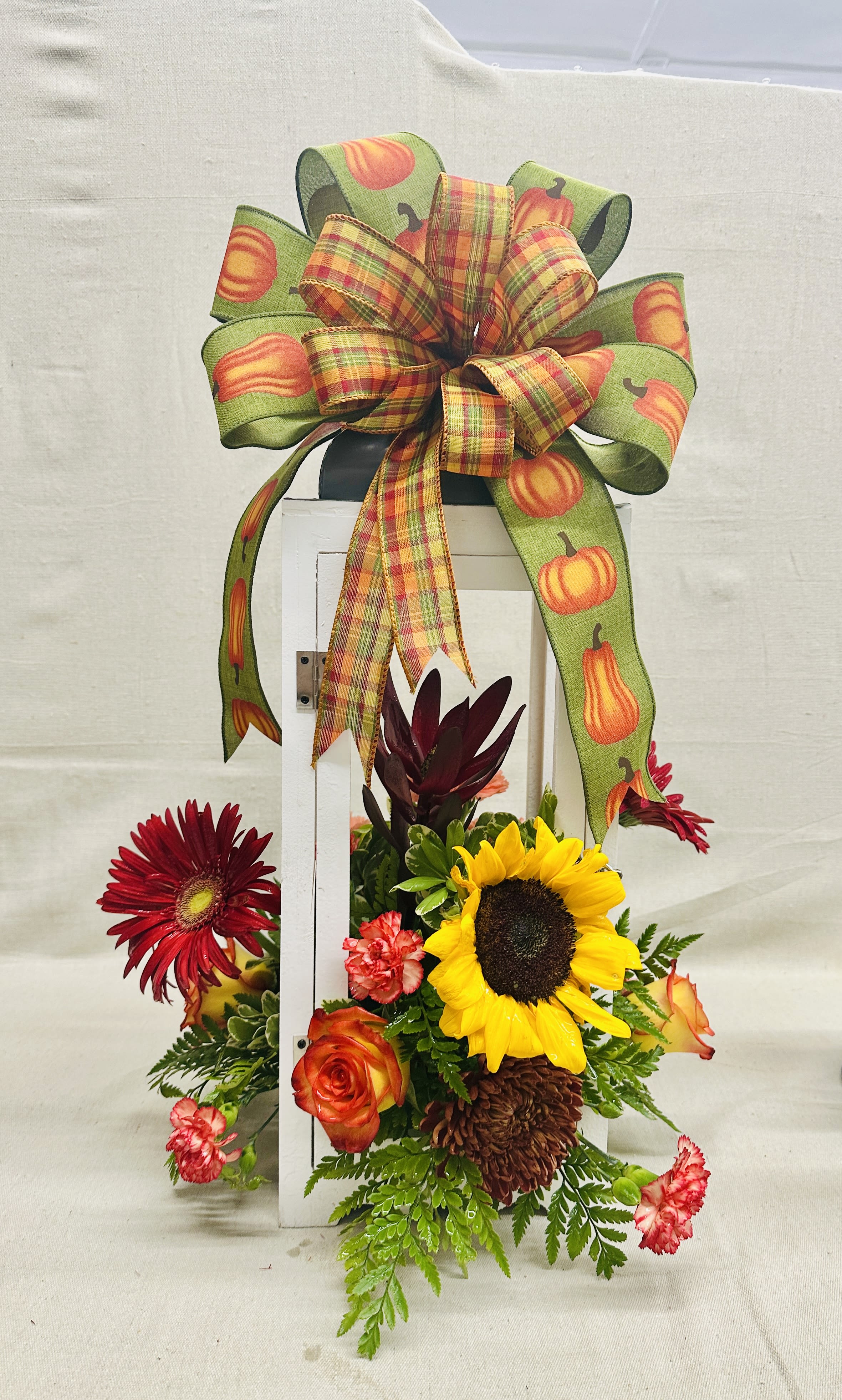 Fall floral arrangement with sunflowers, roses, and a pumpkin ribbon bow