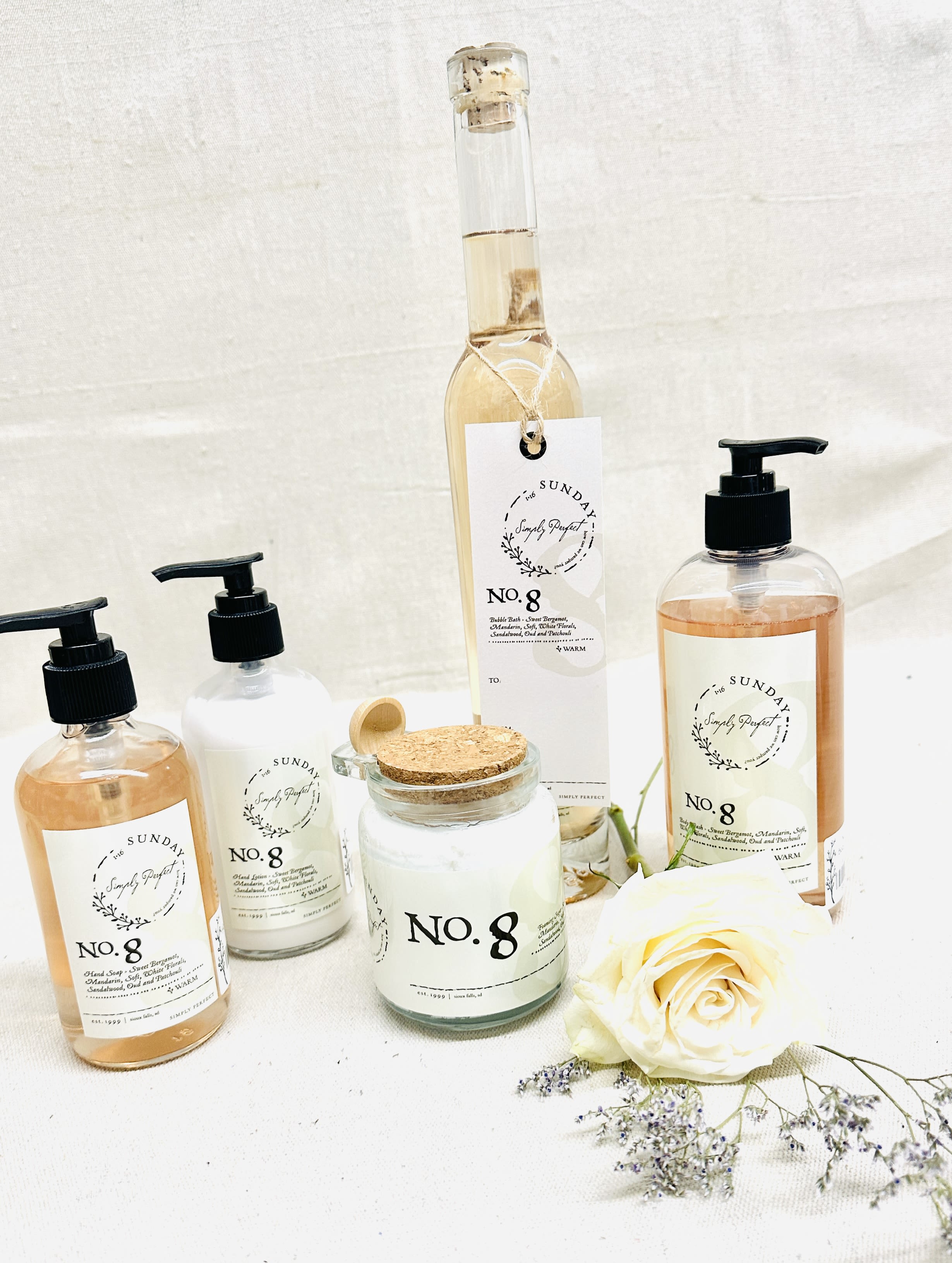Soap bottles and a candle with a white rose