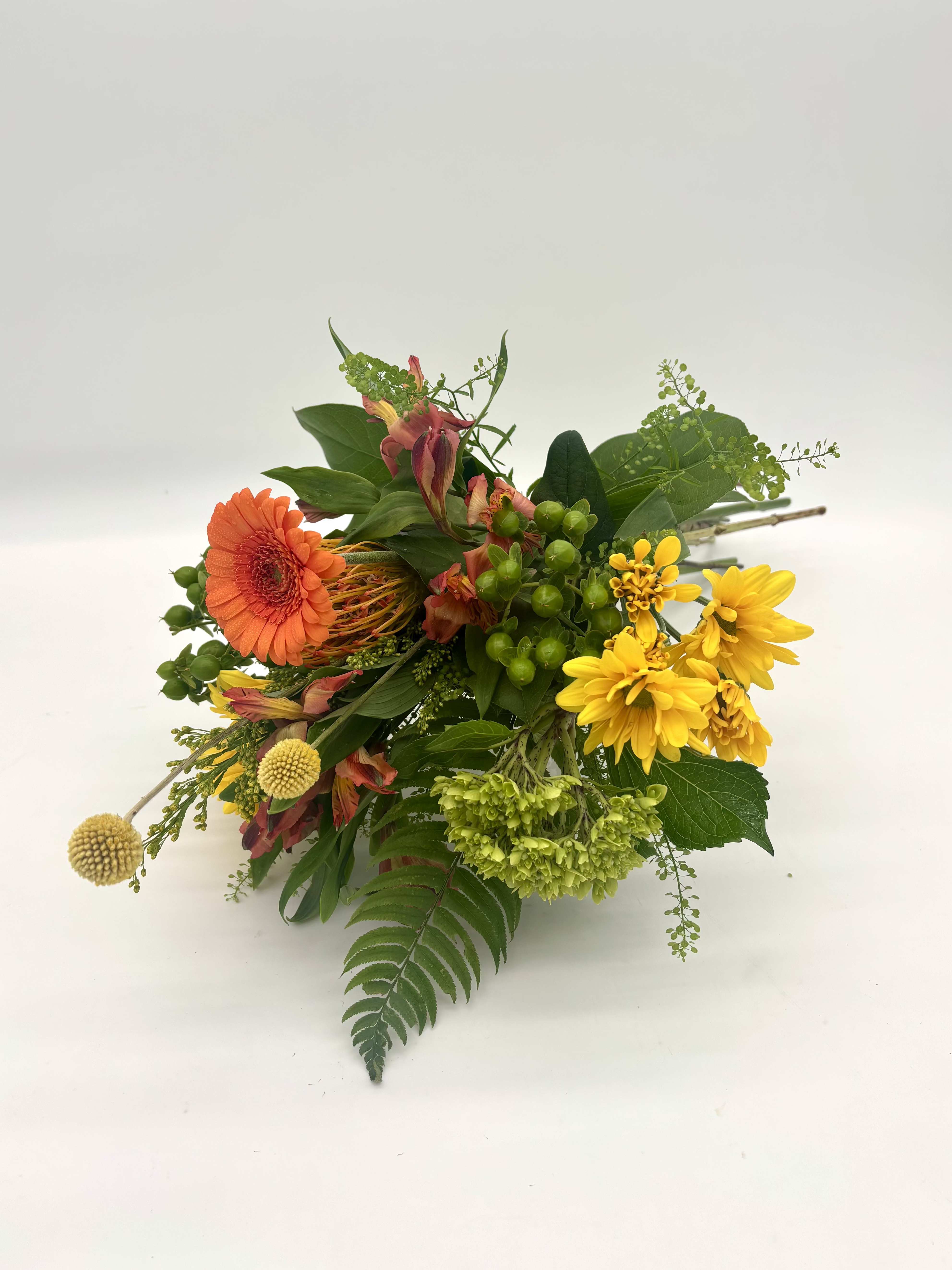 Citrus Zest Wrapped Bouquet - Citrus Zest is a bright, cheerful wrapped bouquet bursting with sunny yellow, vibrant orange, and fresh green blooms. Full of texture and color, it's a joyful gift that brings a refreshing pop of color just because.