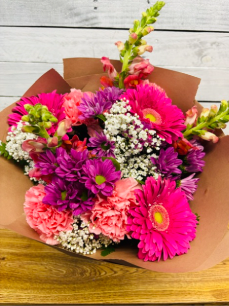 Visser's Pretty and Pink Handheld Bouquet  - Visser's Pretty and Pink Handheld Bouquet is a mix of pink and lavender seasonal flowers with greenery and baby's breath wrap in brown paper and delivered in a glass vase.  Some flowers may be substituted depending on availability. Flower do changes as seasons and availability on flowers change. Overall look and feel of the handheld will be honored. 