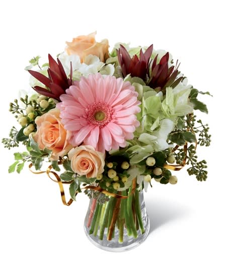 Bouquet of pink gerbera daisies and peach roses in a glass vase