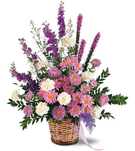 Pink and white mixed flowers in a wicker basket with a ribbon