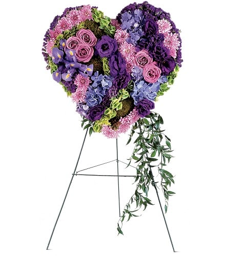 Heart-shaped floral standing spray in purple and pink tones on an easel