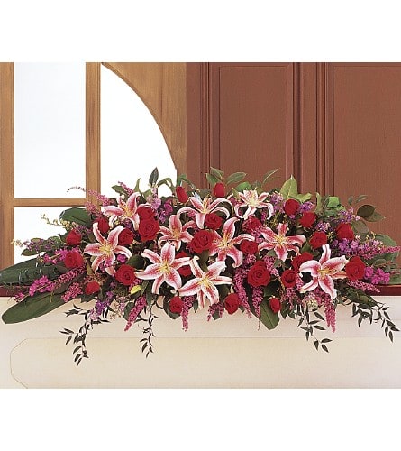 Long floral arrangement with red roses and pink lilies in a white container