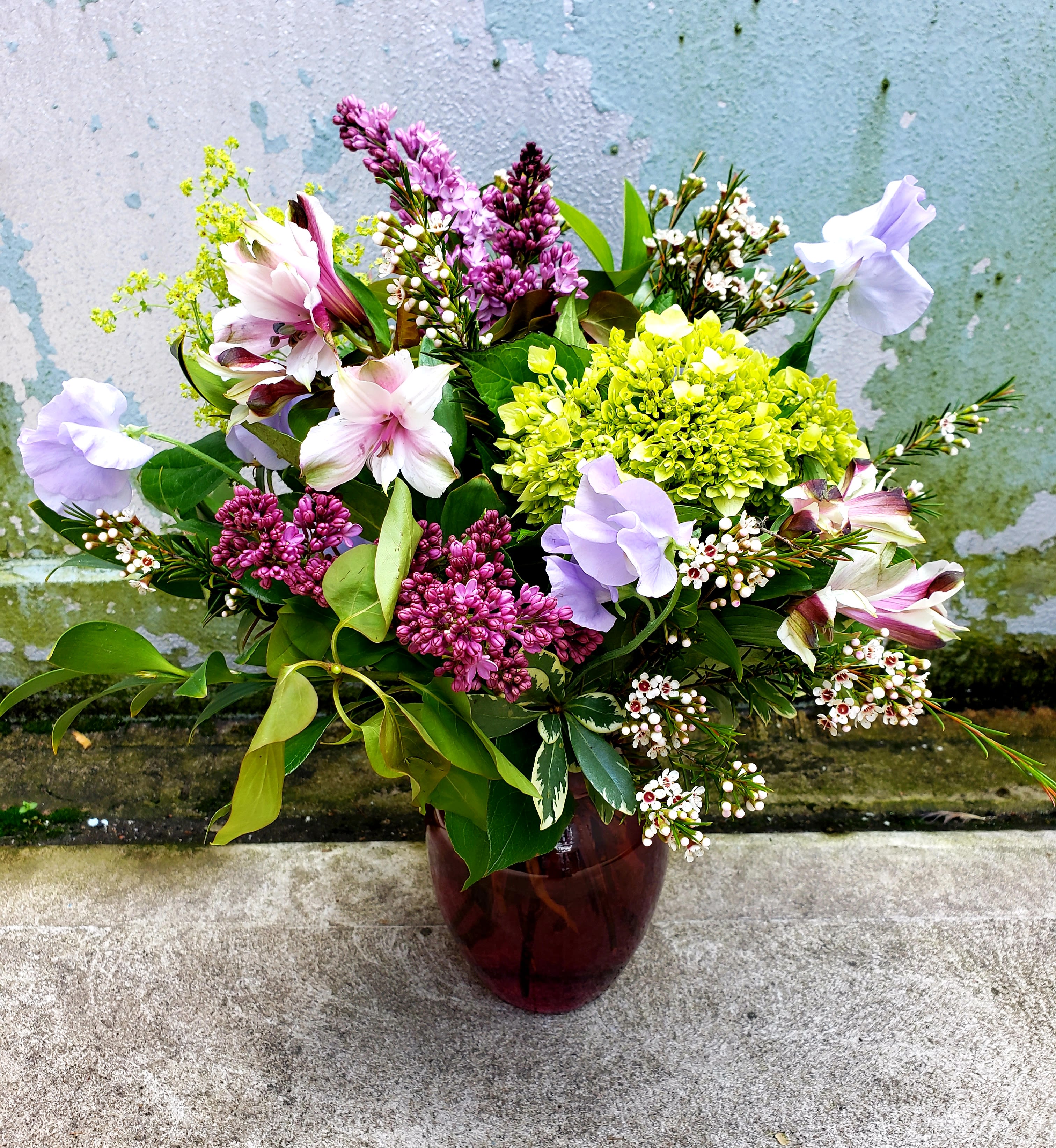Mixed bouquet in a dark glass vase with pink, purple, and white blooms