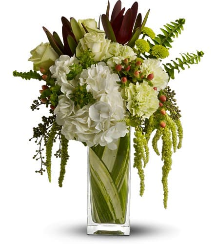 White and green floral arrangement in a tall glass vase