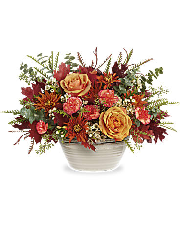 Autumn floral arrangement in a white ceramic bowl with orange and red blooms