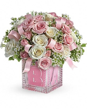 Baby's First Block by Teleflora - Pink - Celebrate the cutest baby girl on the block's arrival with this charming glass baby block that arrives chock full of pretty flowers. Perfect for baby showers, too! The glass block will make an adorable display piece for years! Pretty light pink and white spray roses, waxflower and pink satin ribbon are delivered in a clear baby block with a pink liner. One amazing delivery deserves another, don't you think?
