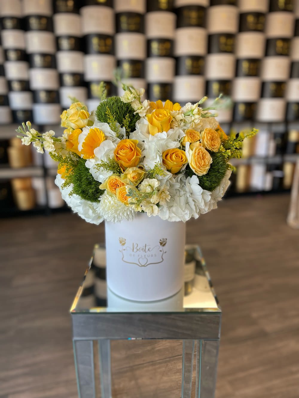 Yellow and white floral arrangement in a white hat box