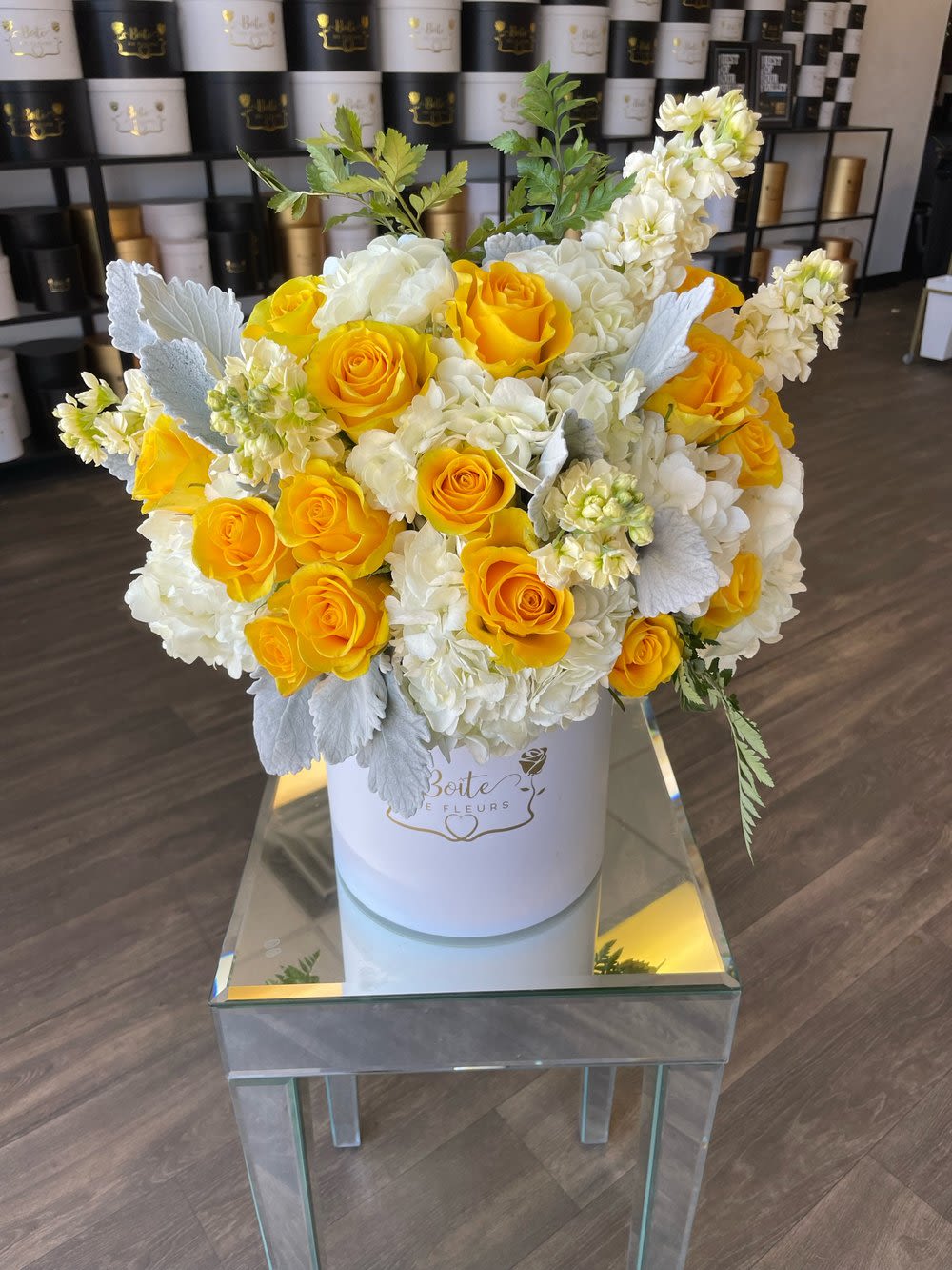 Yellow roses and white blooms arranged in a white hatbox
