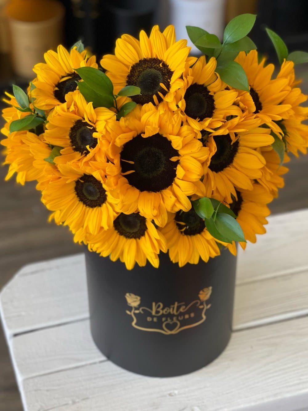 Bouquet of yellow sunflowers in a black hatbox