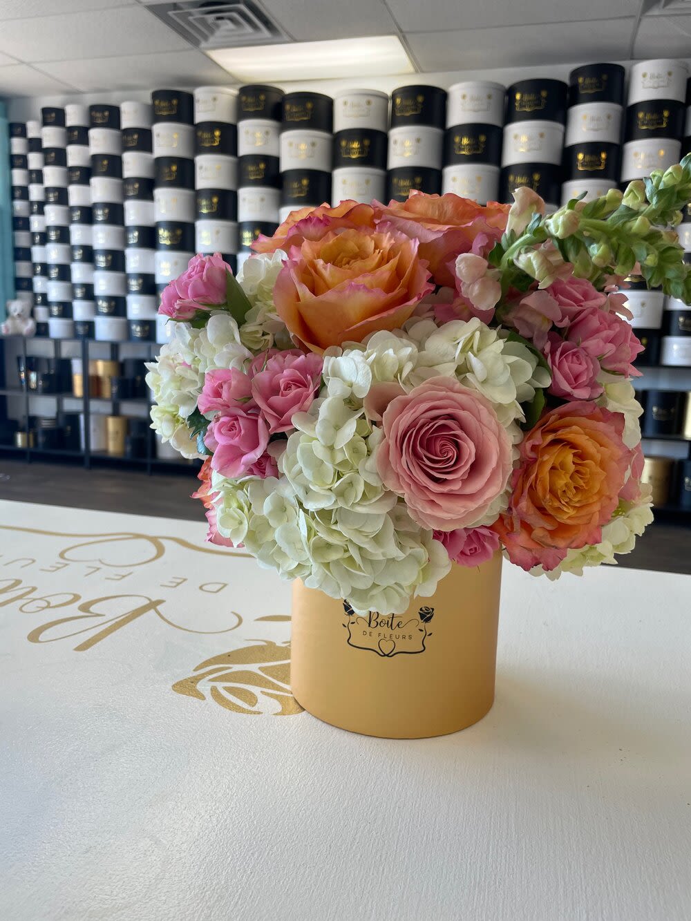 Pink and orange roses with white hydrangeas in a gold box