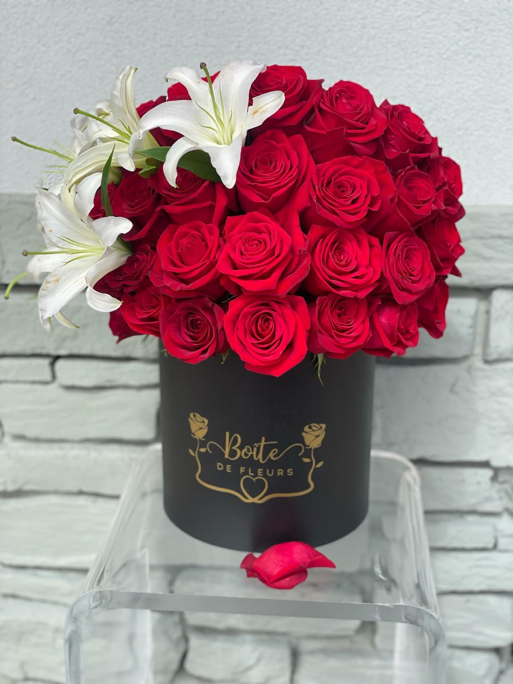 Red roses with white lilies in a black hat box