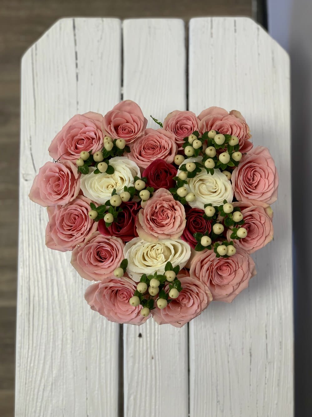 Heart-shaped bouquet of pink and white roses with berry accents