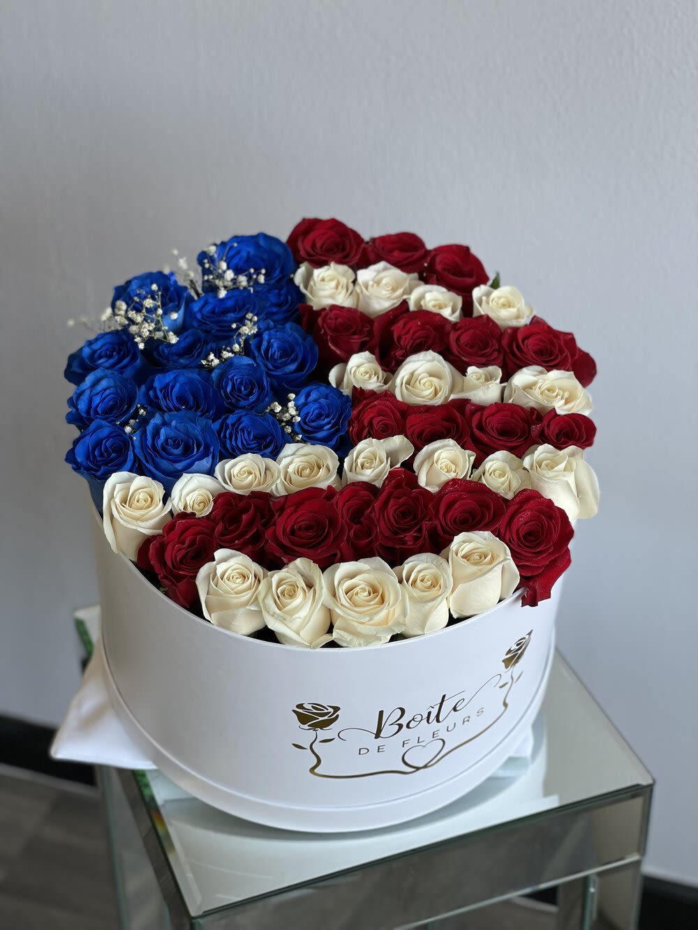 Round box of red, white, and blue roses with baby's breath
