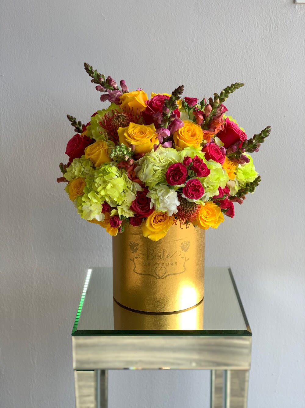 Bright mixed bouquet in a gold hatbox with yellow and pink flowers