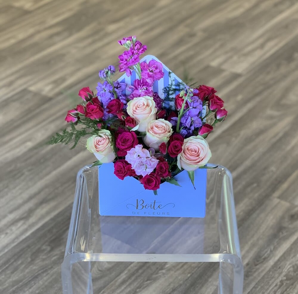 Mixed pink and purple roses arranged in a blue box