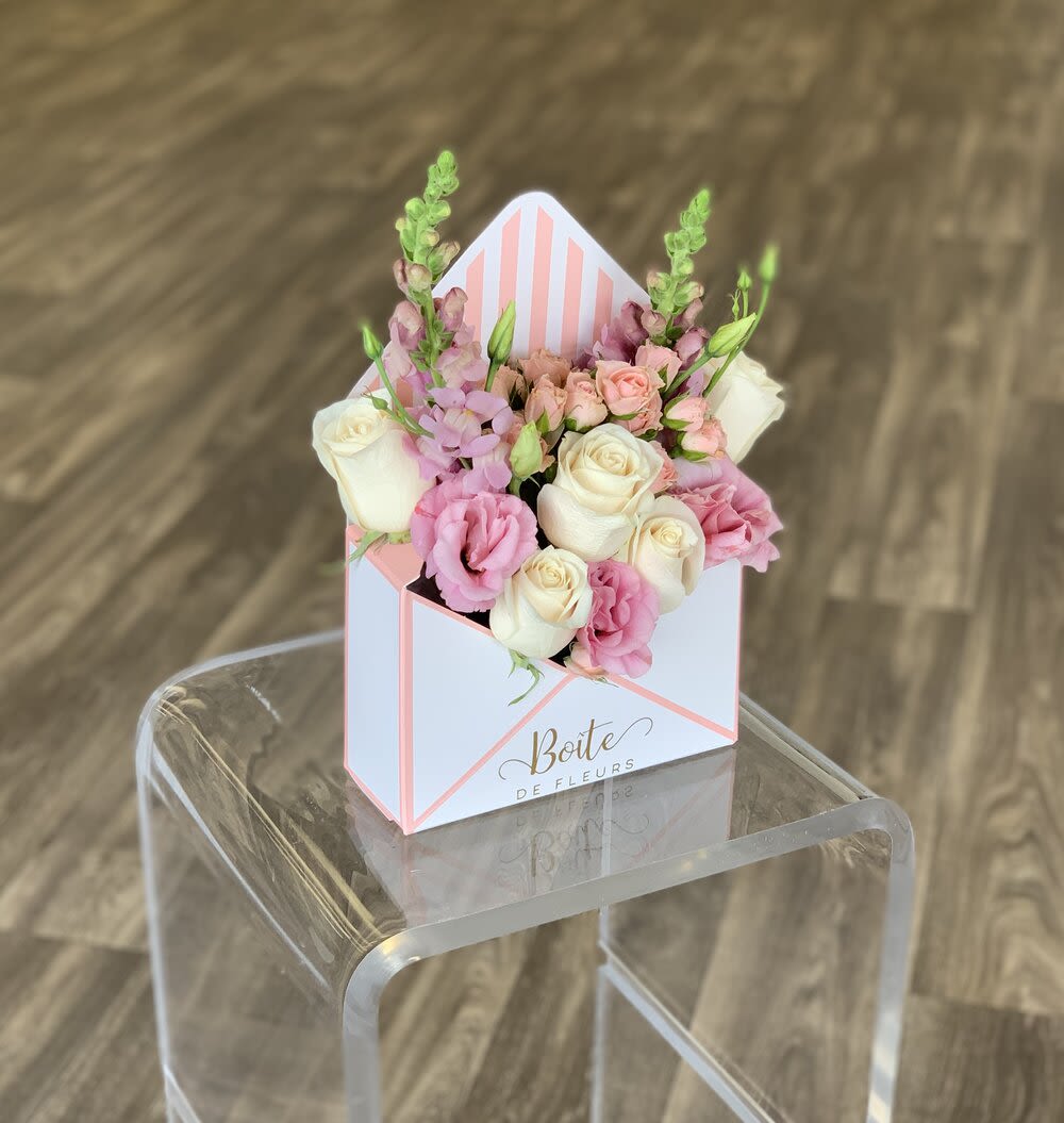Pink and white roses arranged in a striped gift box