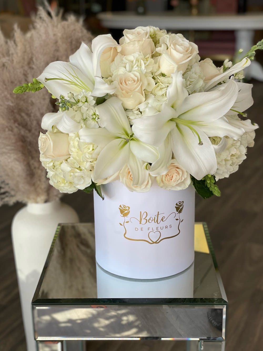 White lilies and cream roses arranged in a round white box