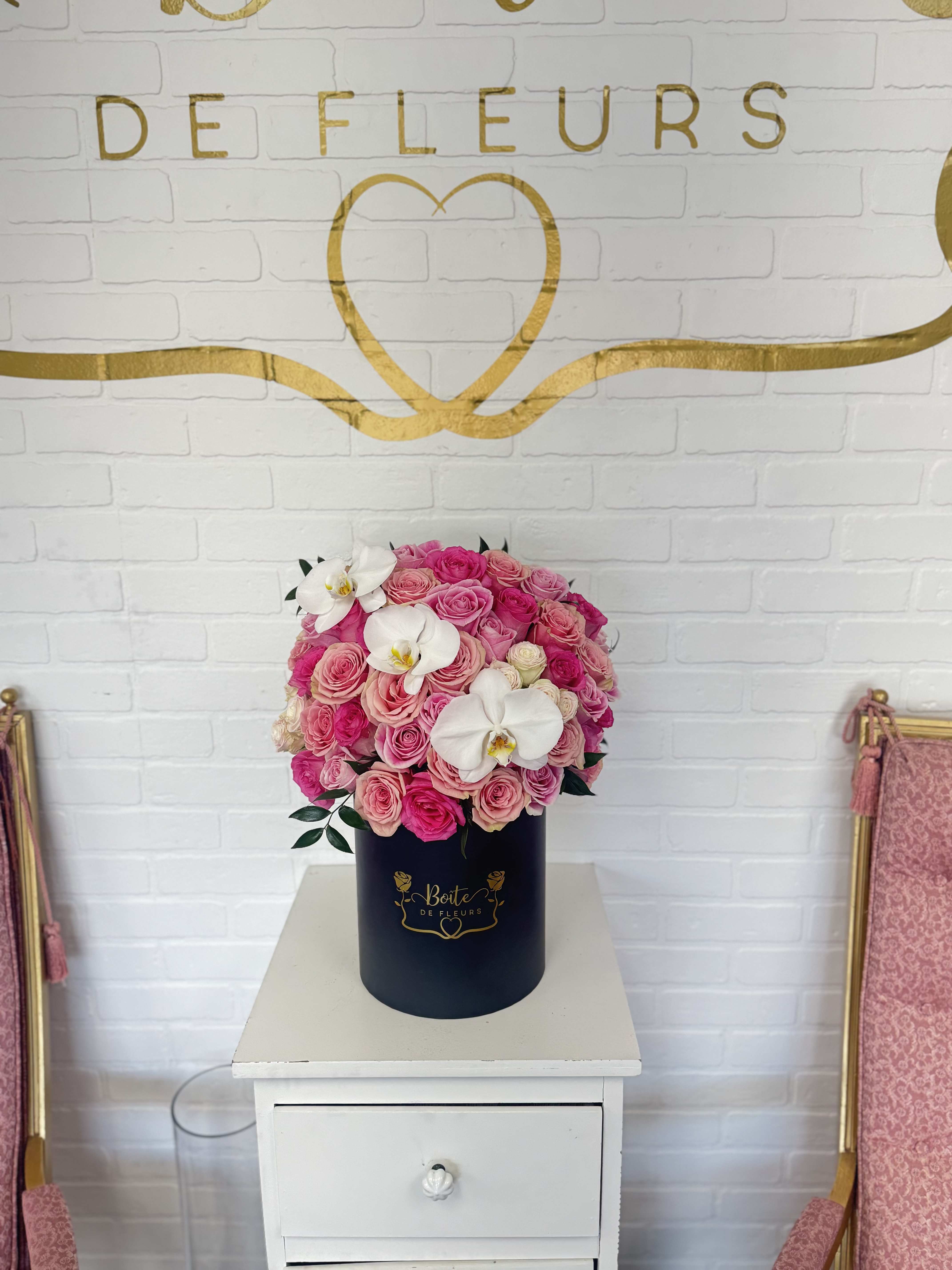 Pink rose arrangement in a navy cylindrical box with white orchids