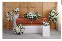 White funeral floral arrangements around a casket in a room