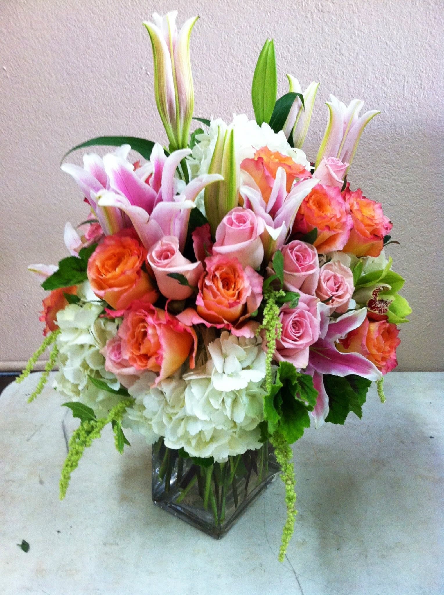 Bouquet of pink and orange roses with lilies in a glass vase