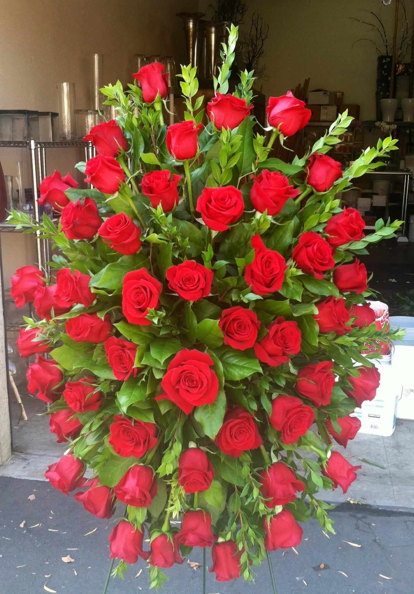 Large standing arrangement of red roses with greenery