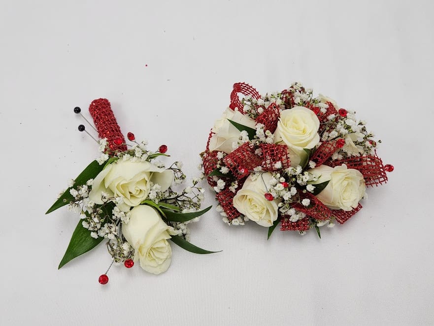 Scarlett Gems Boutonniere and Wristlet Set - Select this bold and beautiful boutonniere set featuring spray roses, babies breathe with accents of bright red rhinestones and sparkly red ribbon. The wristlet corsage will come on a standard grey wristband that is elastic. The boutonniere will come with two black pins to pin on their lapel or shirt.