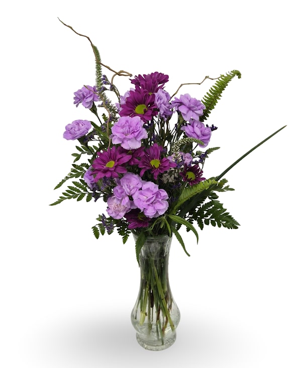 Simply Love - A cheerful, slightly wild upright arrangement that feels like a fresh garden-picked surprise-perfect as simple gesture. This flower arrangement is designed for Mother's Day or Valentine's Day moments when you want her to feel seen: purple and lavender tones punctuated with, green, and white create a calm yet joyful impression the recipient will treasure.  Made with mini carnations, chrysanthemums, veronica, curly willow and sword fern, the blooms are layered for height and movement in a simple clear glass bud vase (dimensions 22 x 6 x 4). The natural texture and loose silhouette suit bedside tables, mantels, or nursery corners; minimal care-fresh water and a trim every few days-keeps it looking lovely.
