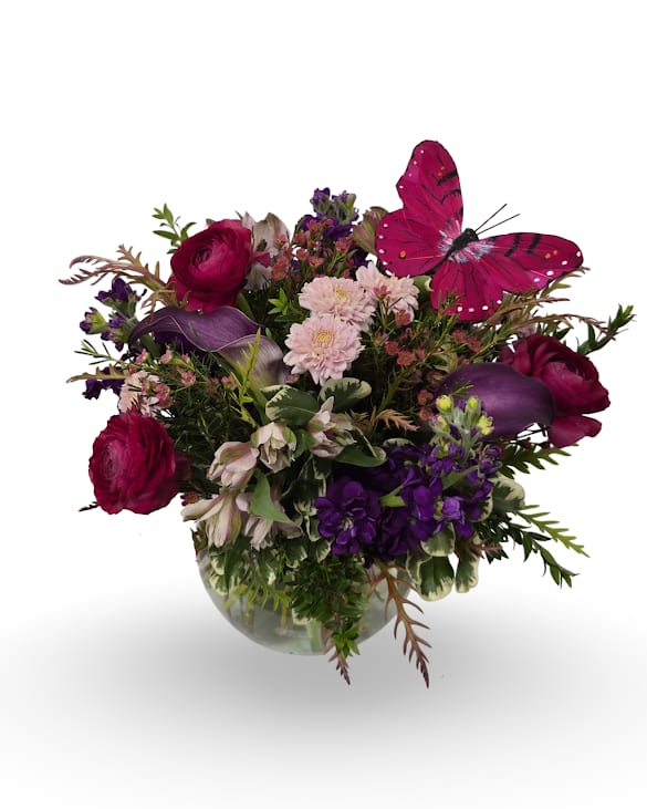 Butterfly Sanctuary - Bright, garden-style flower arrangement ideal as a birthday bouquet, anniversary surprise, or a "just because" gift that will make the person you're thinking of feel truly celebrated. This rounded clear rose bowl features calla, stock, alstroemeria, ranunculus, chrysanthemums, and waxflower, accented with a decorative butterfly for a playful finishing touch.  Full and layered with varied textures, it arrives ready to display in a clear glass vase-perfect for brightening a table, desk, or bedside and sized to make an immediate visual impact without overwhelming the room. Dimensions 13" x 17".