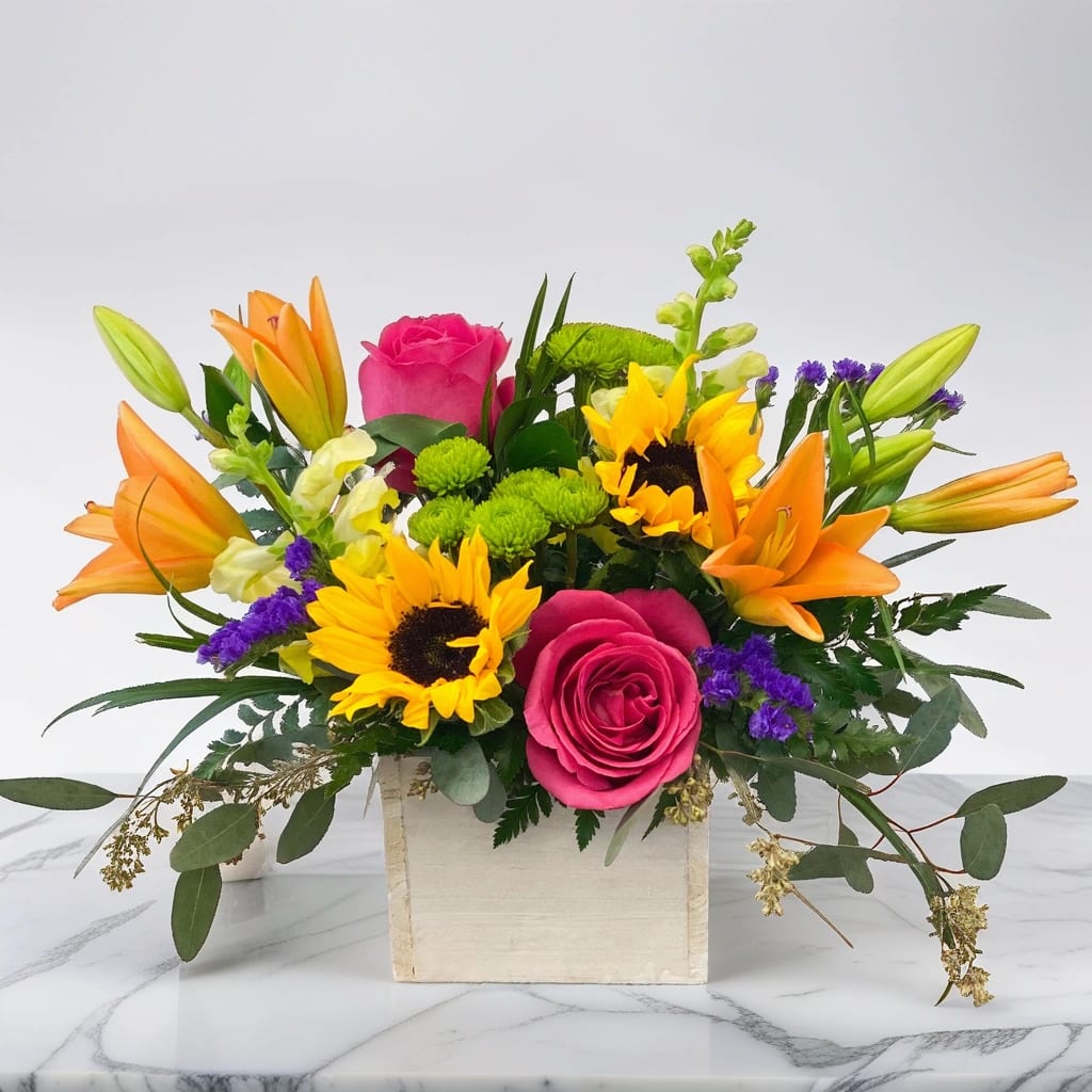 Best Days Wood Box - Wish you could box up a great day and send it to that special someone? Now you can with Hignight's Best Days arrangement. This stunningly colorful display of flowers comes in a white wood box and features sunflowers, hot pink roses, and bright orange lilies.  Our customers love us because we have the best flower delivery in the Quad Cities to get them the freshest blooms on time-- It’s because we have the very best drivers who know the ins and outs of East Moline and the surrounding area!  Hignight Florist delivers flower arrangements, wedding flowers, funeral flowers, plants, and gifts in the Quad Cities: East Moline, Moline, Rock Island, Milan, Coal Valley, Silvis, Carbon Cliff, Hampton, Colona, Bettendorf, and Davenport.     Please Note: The bouquet pictured reflects a Hignight's original design for this product. While we always try to follow the color palette, we may replace stems to deliver the freshest bouquet possible, and we may sometimes need to use a different but simlilar vase. 