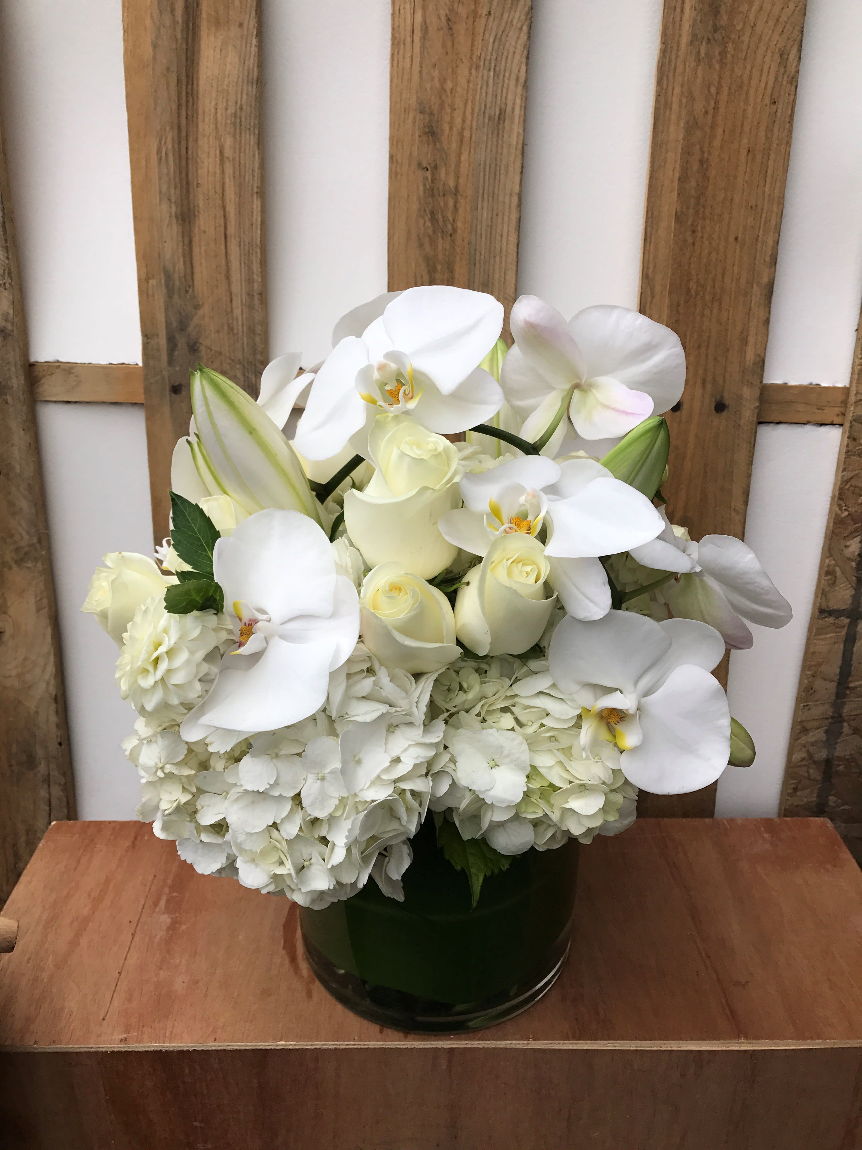 White orchid and rose arrangement in a dark glass vase