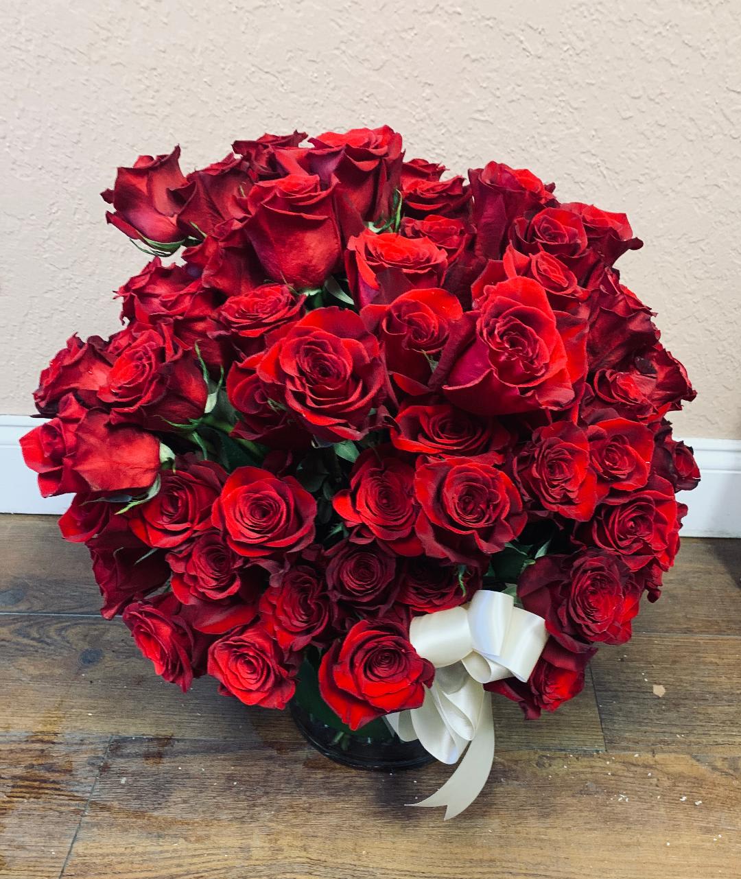 Bouquet of red roses with a white ribbon in a glass vase
