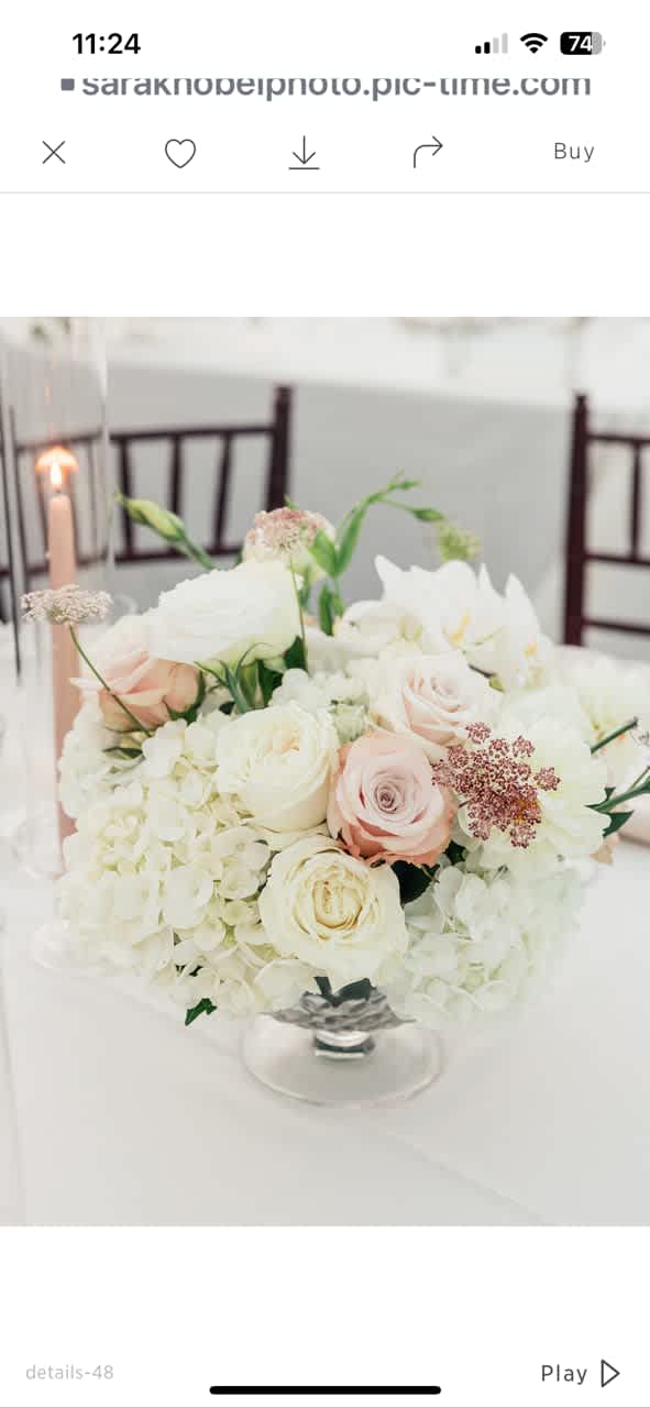 Whimsical Whites - A low, rounded centerpiece built from clouds of white hydrangeas and blush-to-ivory roses, this wedding or formal event centerpiece makes the person you're celebrating feel cherished and elegantly seen. Whimsical Whites is a centerpiece or table arrangement designed for weddings, anniversary dinners, and other refined gatherings where a soft, romantic mood is the goal.  The arrangement sits in a clear glass vase and features white hydrangeas, several blush-to-ivory roses, and small airy filler blooms for delicate texture; a few pale green buds and stems lend a fresh, garden-style touch. The mostly-white palette with gentle pink accents keeps the look light and refined, pairing beautifully with a neutral table setting or candlelight.  Perfect for reception tables, a head-table accent, or an intimate anniversary dinner, this low, rounded centerpiece is sized to encourage conversation while anchoring the setting with classic romance. It arrives ready to display in its clear glass vase; add nearby table candle holders and candles to amplify the warm, inviting glow.