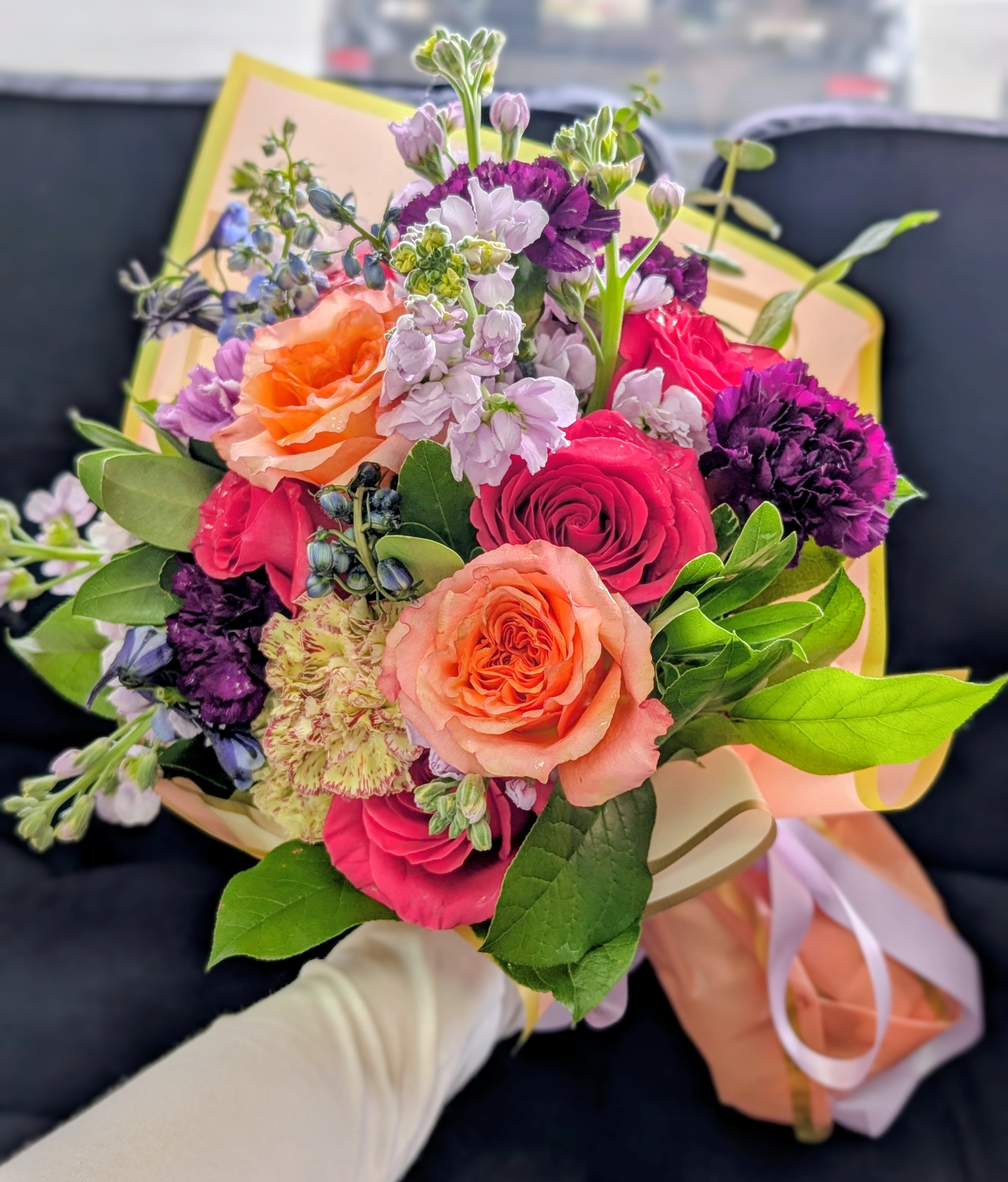 Hand-tied bouquet of pink, peach, and purple flowers with ribbon wrap