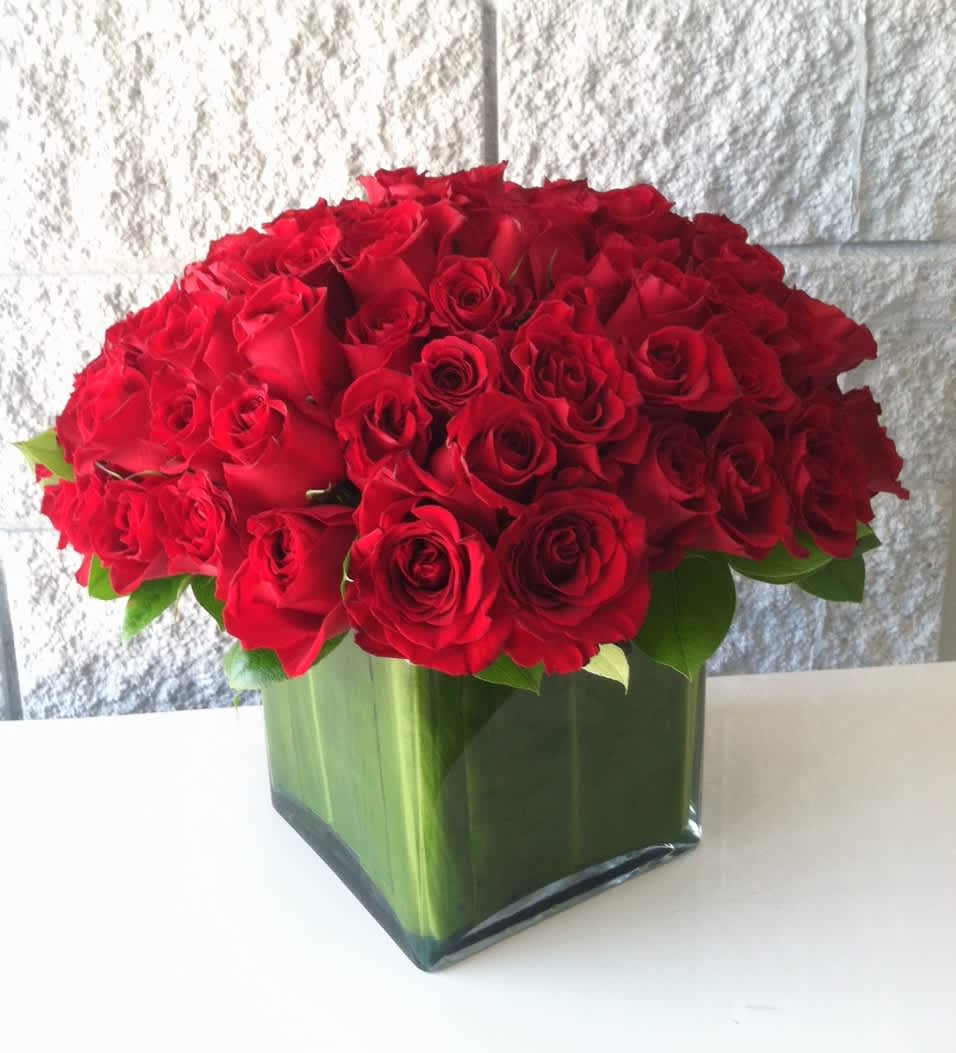 Love Squared (BB) - Make a grand romantic gesture with our stunning product: 100 red roses arranged in a huge leaf-lined glass vase. This enchanting arrangement is sure to capture the heart and leave a lasting impression.