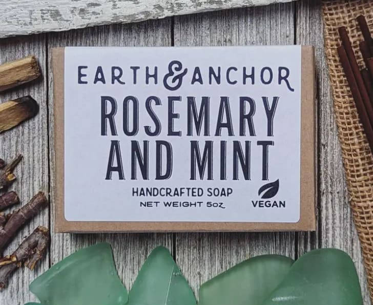 Bar of handcrafted rosemary and mint soap on a rustic wooden surface